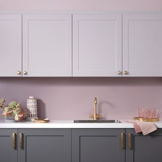 a pink kitchen with grey cabinets, marble surface, and pink accessories