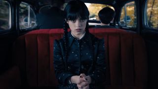 Jenna Ortega as Wednesday sitting in a car doing her signature stare. 