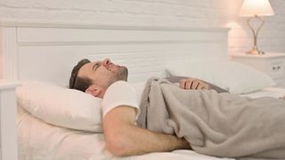 A person lying in an uncomfortable bed