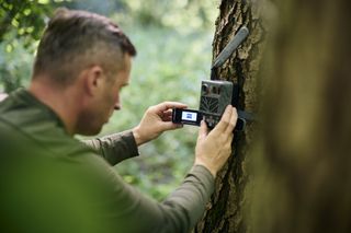 an individual setting up the Zeiss Secacam 3 outdoors on a tree in a forrest