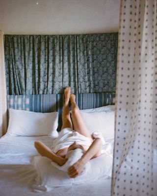 Content creator Emma Hoareau laying on a hotel bed in a towel.