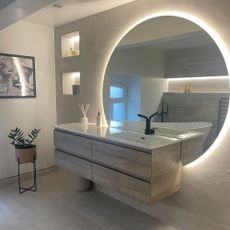 en suite bathroom with large vanity and round mirror