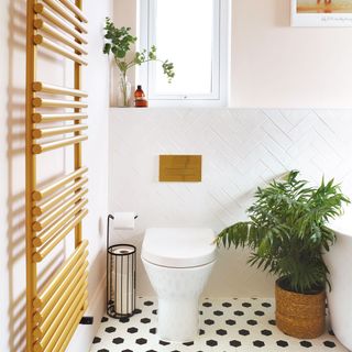 Gold towel radiator and white builtin wc with gold coloured flush plate