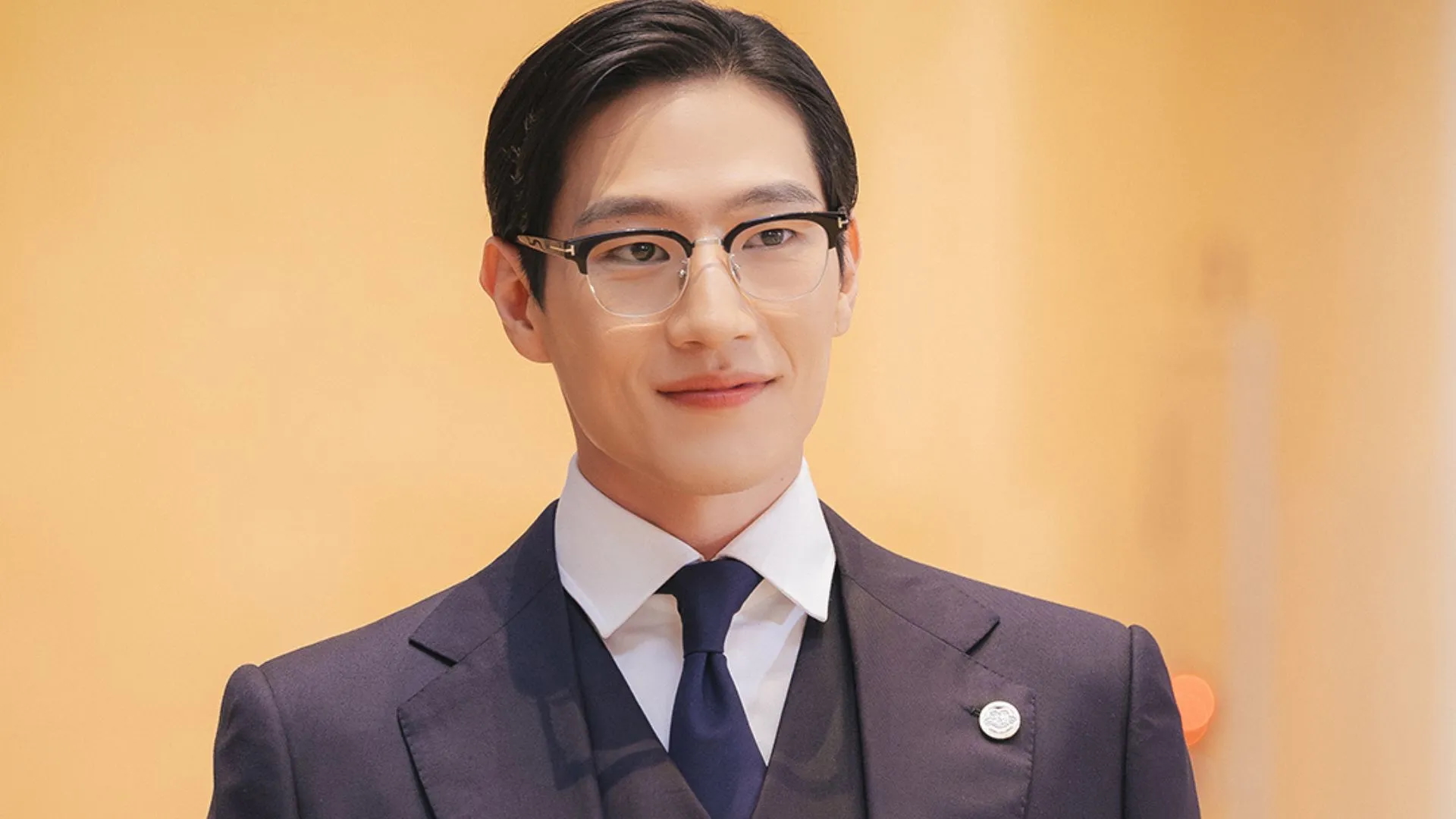 Steve Sanghyun Noh in 'Perfect Crown' wearing. asuit tie and glasses