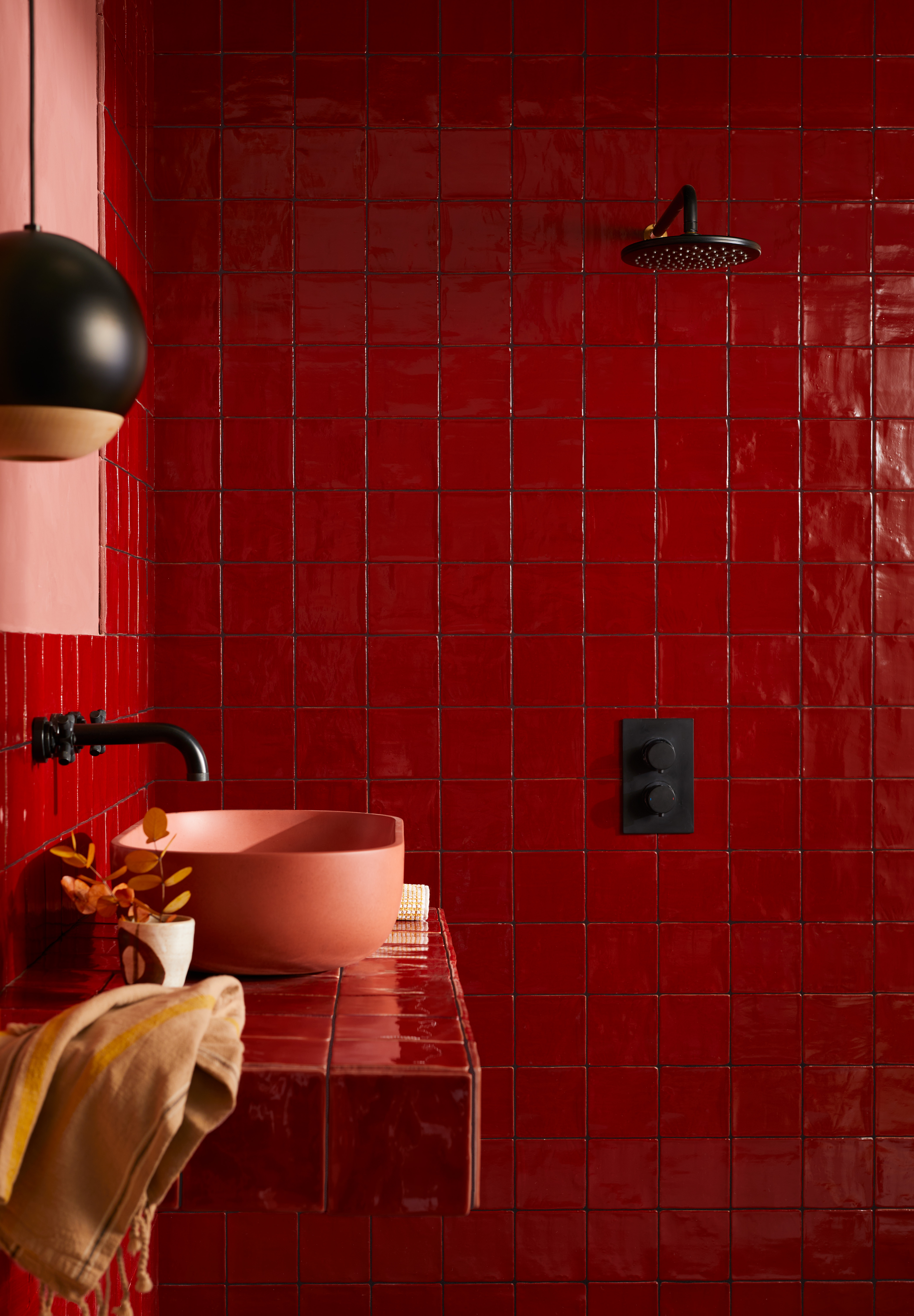 A square format tile in red with a sink in the bathroom and a shower. 