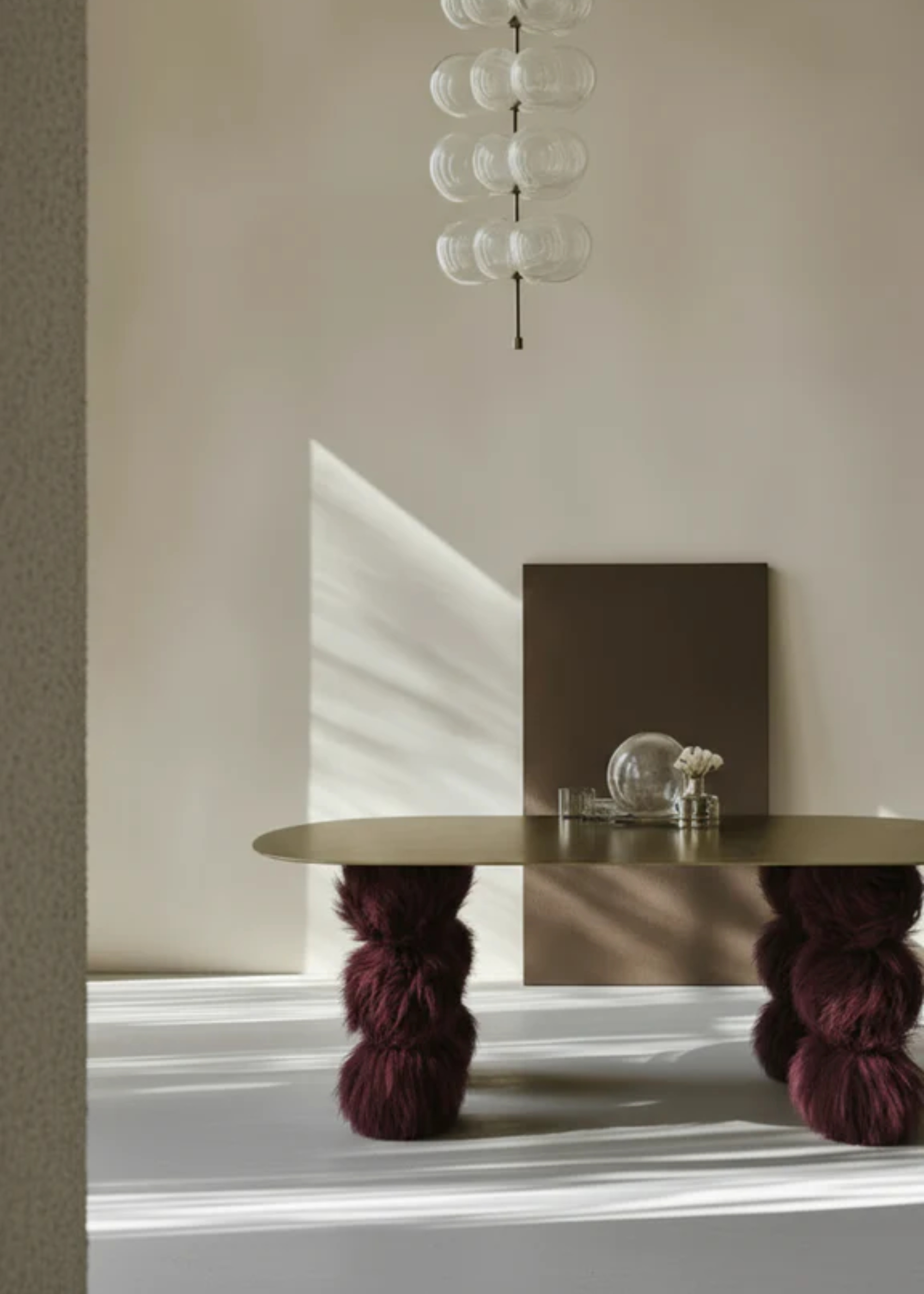 A bright living room with a thin brass table top and fuzzy stacked legs