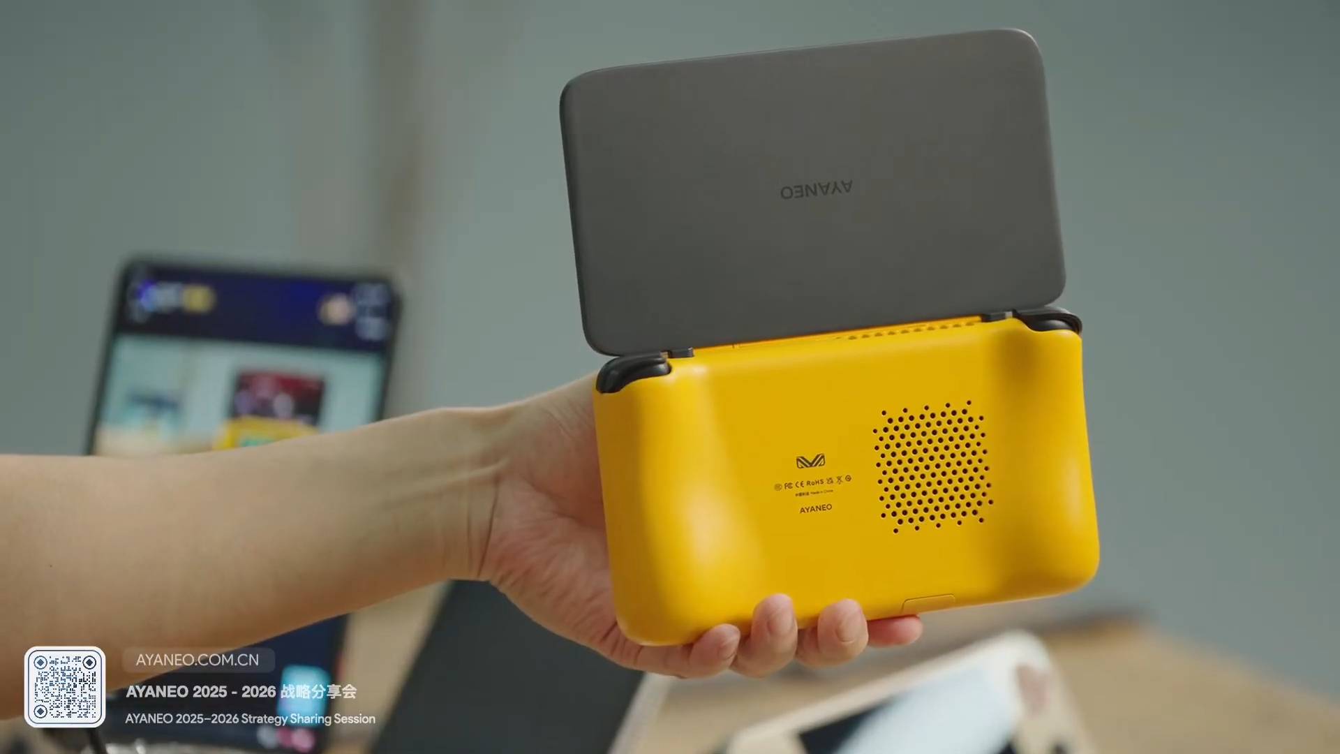 Close up of hand holding yellow Ayaneo Pocket DS with back facing camera.