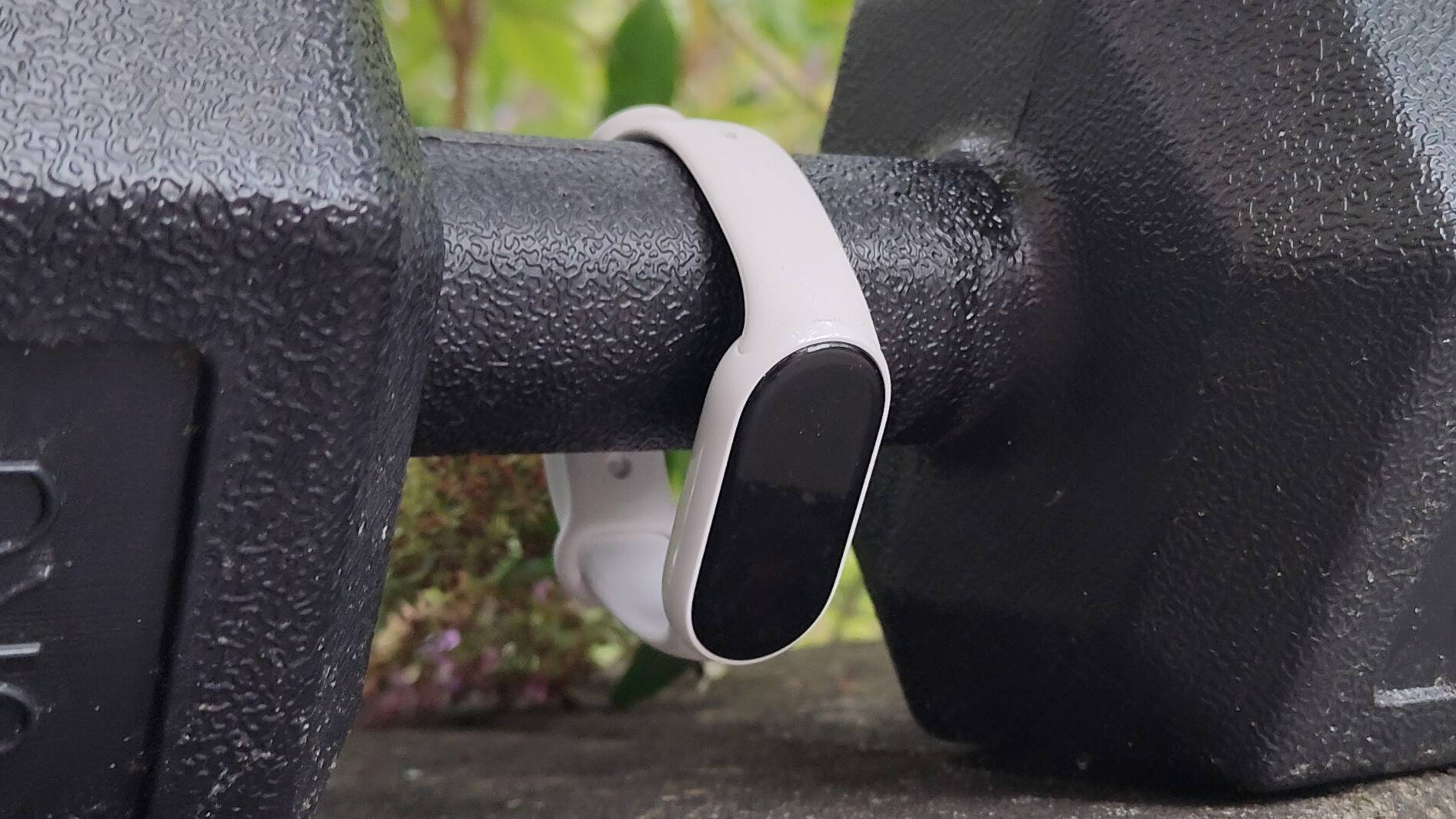 The Xiaomi Smart Band 10 strapped to a dumbell.