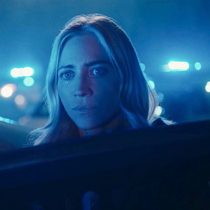 brittany snow gets out of a car as police lights light up blue around her in a still from the hunting wives season 2
