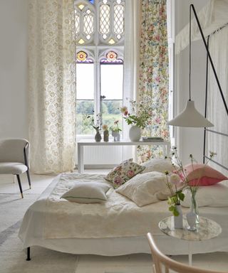 bedroom window ideas, neutral bedroom with textures, cream layers, two different curtains, draping over bed, stained glass window, white console table