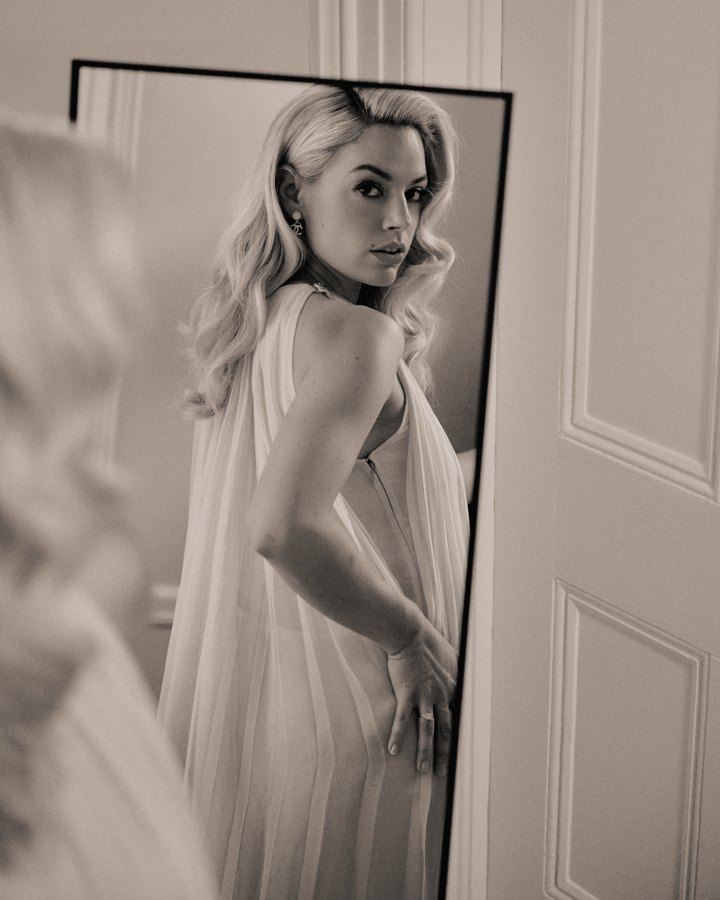Ashe stands in front of a mirror in a black and white filter