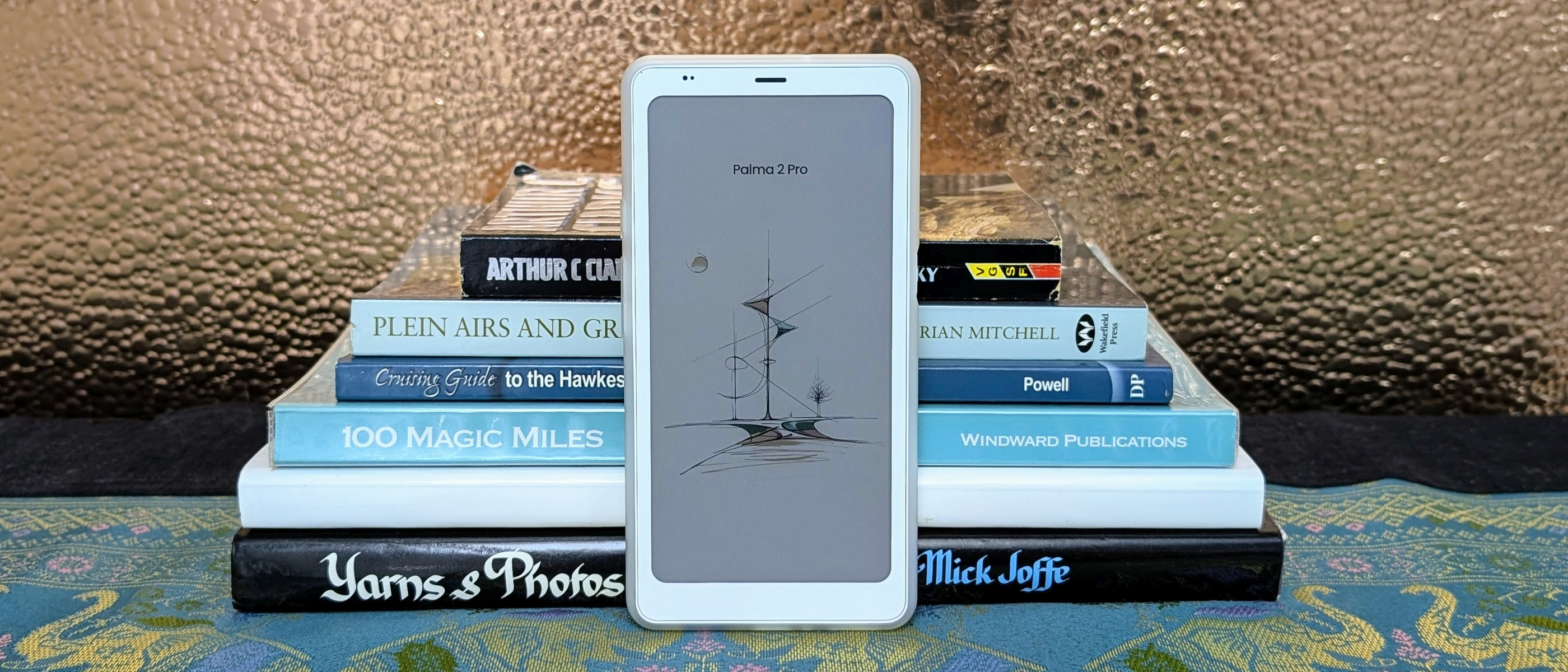 Boox Palma 2 Pro ereader in front of a stack of books