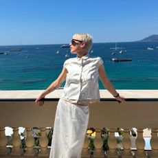 @emmachamberlain wears a white cotton short sleeve blouse with a white skirt.