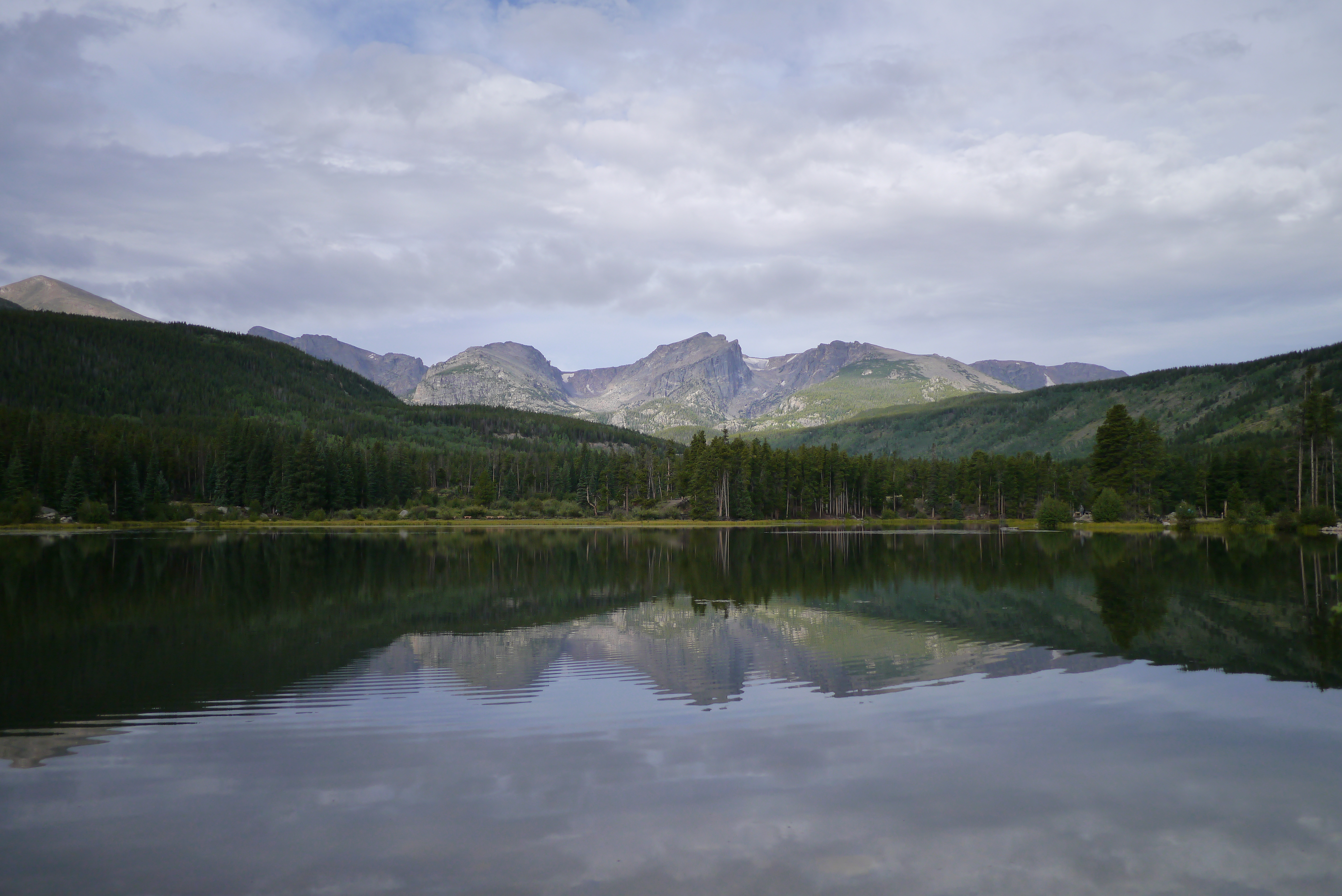 A mountainous landscape with a lake and forest in the lower half of the scene