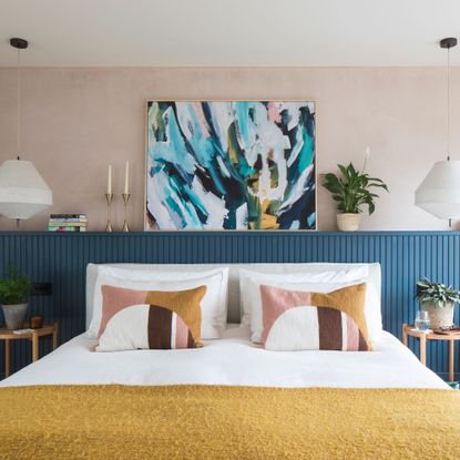 Pink bedroom with blue headboard and white double bed with throw cushions
