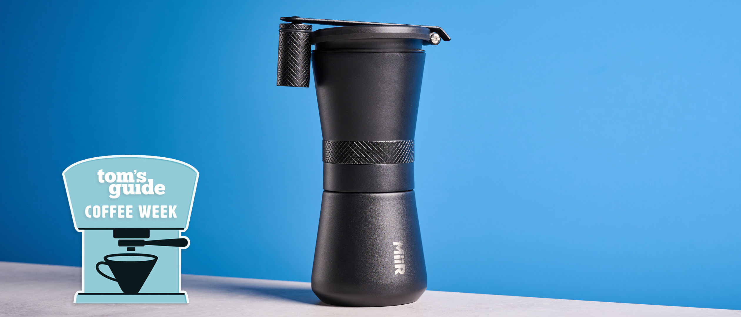MiiR New Standard Hand Grinder in matte black photographed on a blue background with a tom&#039;s Guide coffee week badge