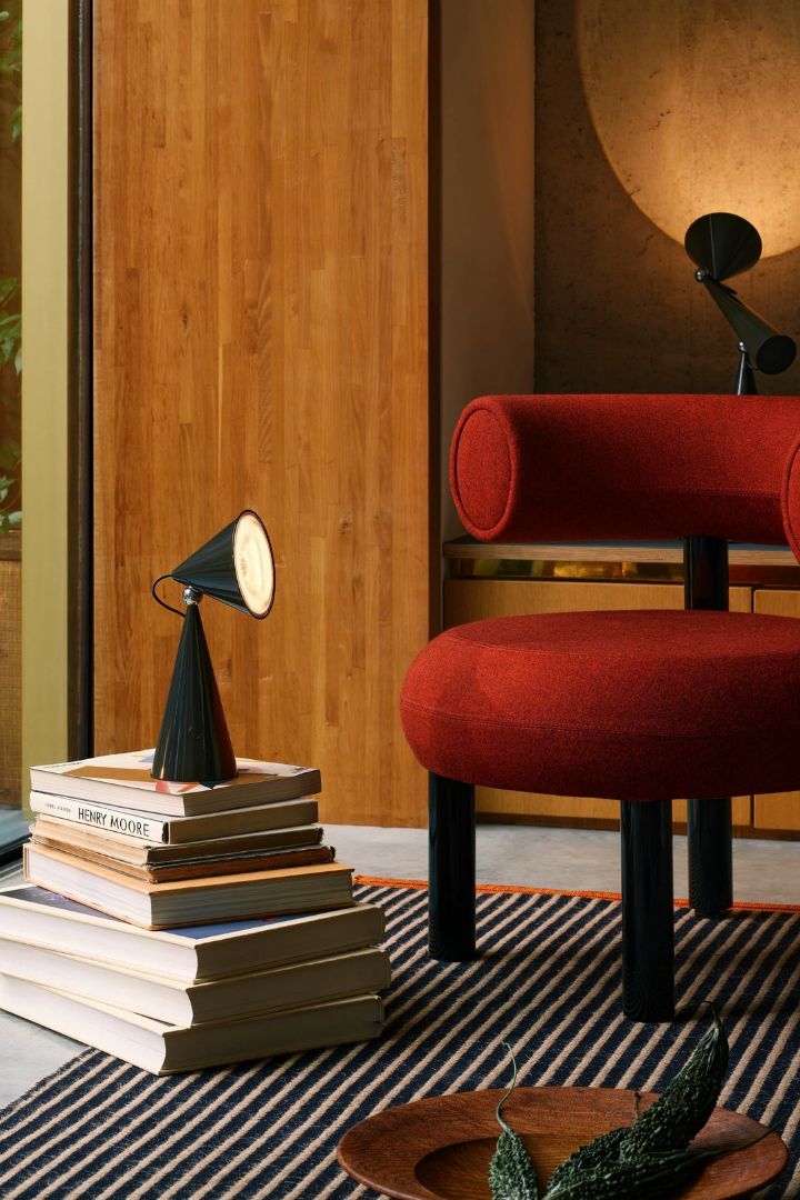 Fat Lounge Chair in Polished Black Steel &amp;amp; Forest Royal Velvet styled inside a hip, modernist living room with wooden shelving, stripy rugs, and books.