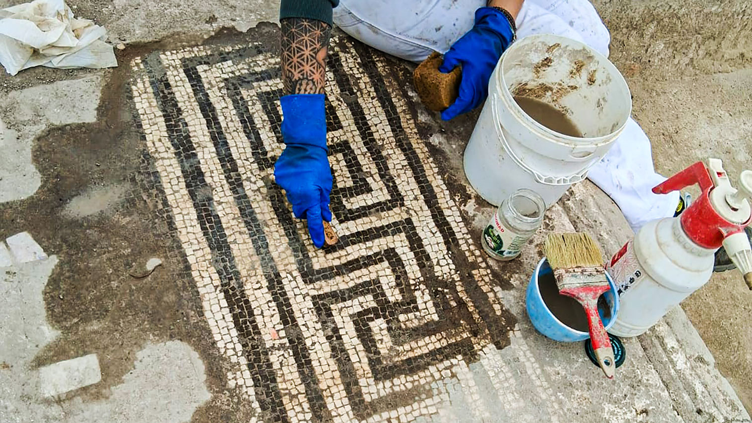 archaeologists work at an ancient Roman site revealing mosaic floors and frescoed walls of a villa
