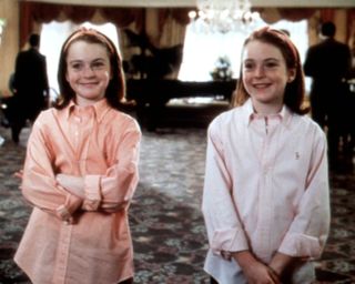 lindsay lohan as annie and hallie standing in a hotel lobby wearing matching polo shirts in the parent trap