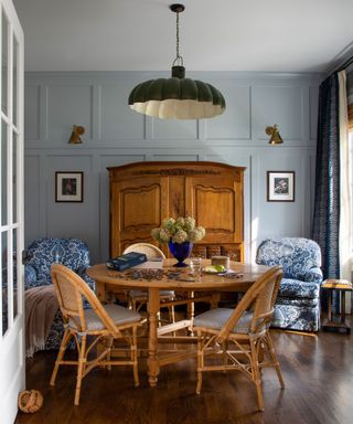 dining room with light blue wall, round wooden table and chairs, vintage dresser