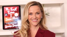 Image of Reese Witherspoon smiling with curled blonde hair to one side and wearing a burgundy blazer