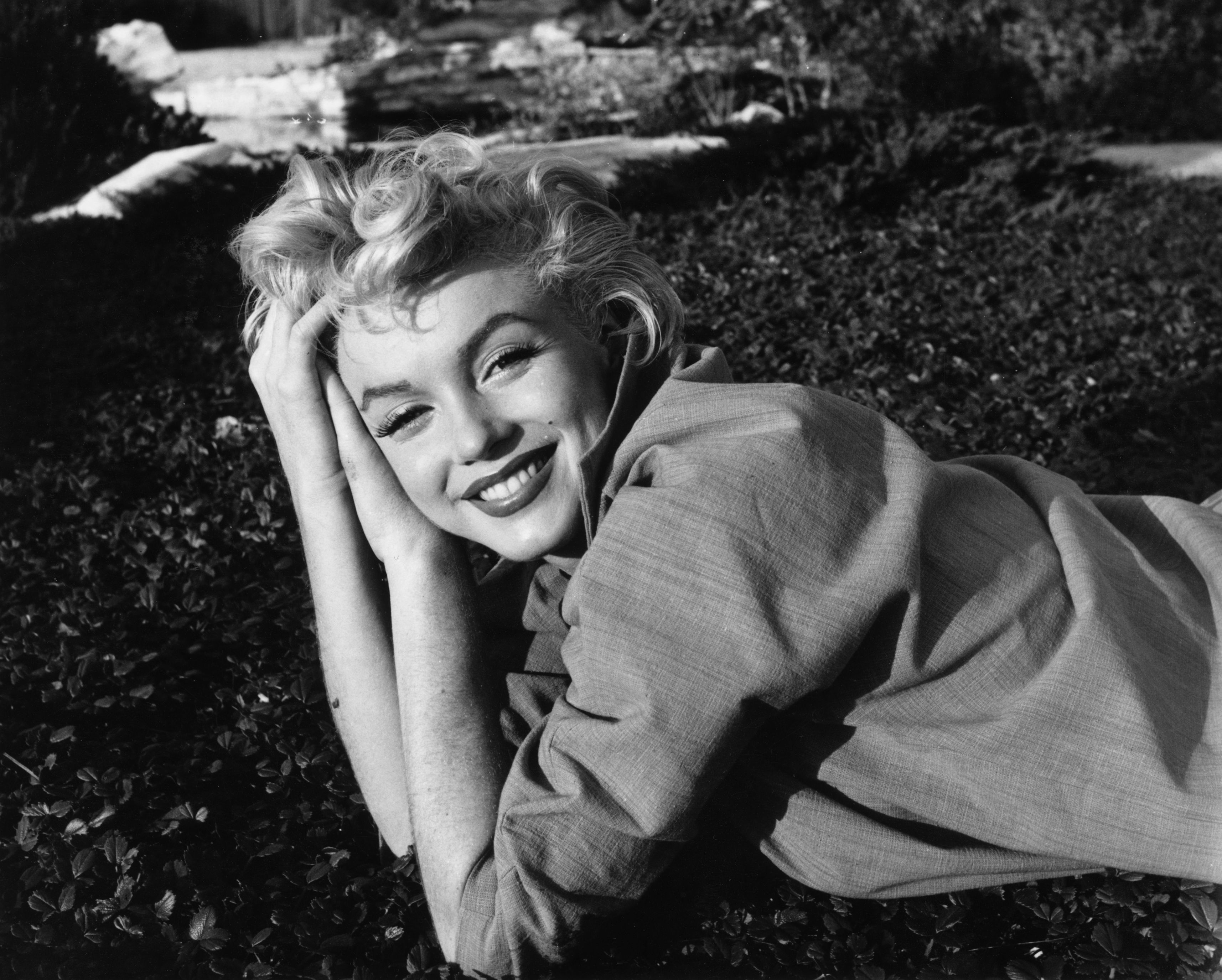 Marilyn Monroe smiles while relaxing on grass