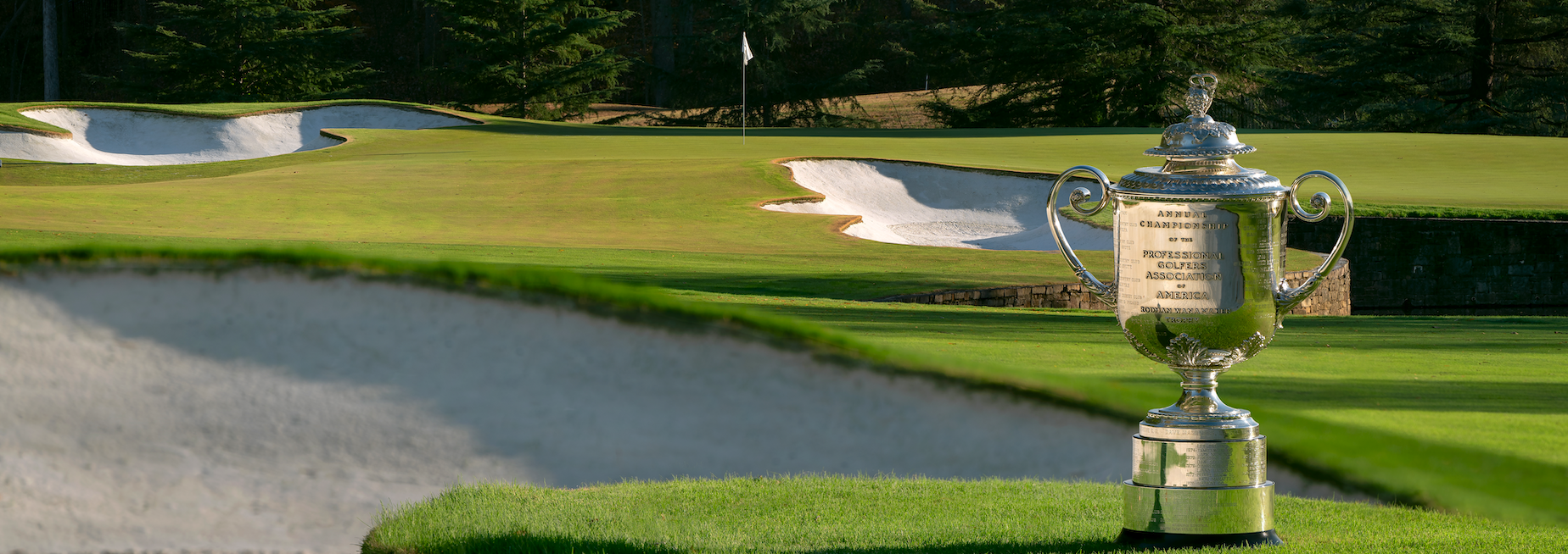 The Wanamaker Trophy seen on a fairway with a bunker and green in the background