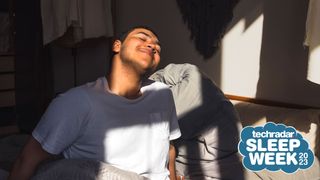 A person waking up happy in the morning with the sun shining on their face. A badge in the corner says 'TechRadar Sleep Week 2023'