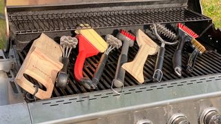 The best grill brushes shown on top of a grill outdoors in a backyard