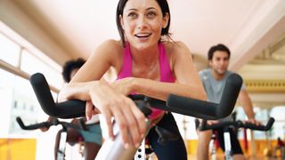 Woman leans forward for a rest on a stationary exercise bike