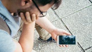 A person holds a phone with a smashed screen