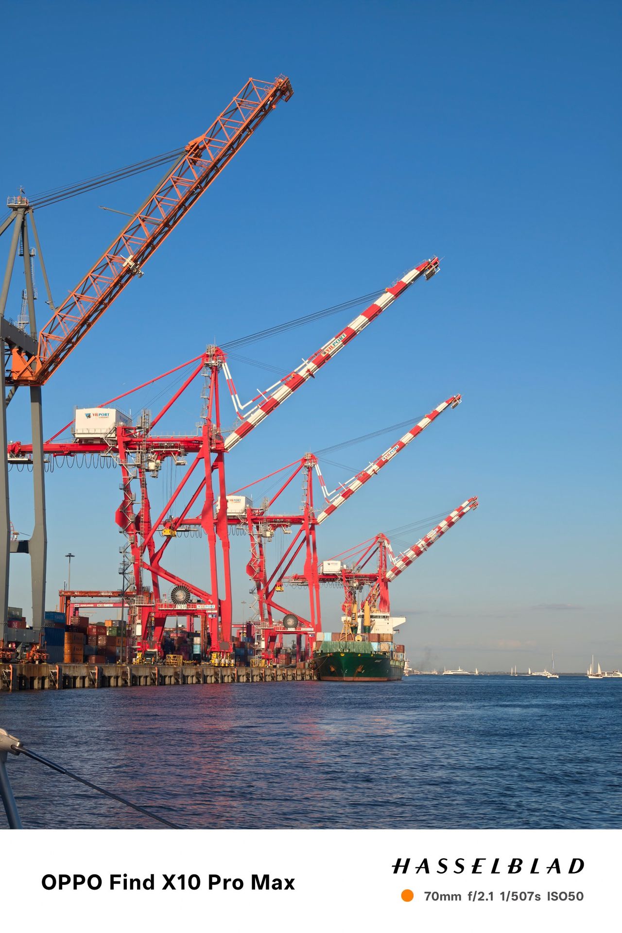 Red container cranes and a cargo ship at Lisbon&rsquo;s port beside the Tagus River.