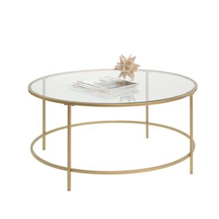 A glass and gold metal coffee table with decor on it