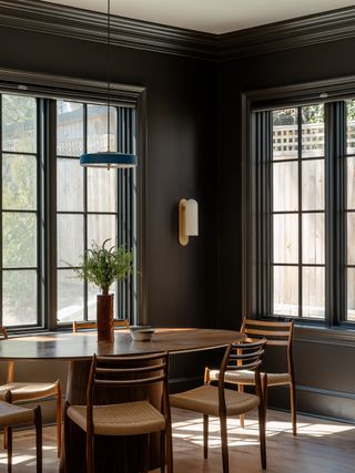 breakfast room with black walls, wooden table and tall windows