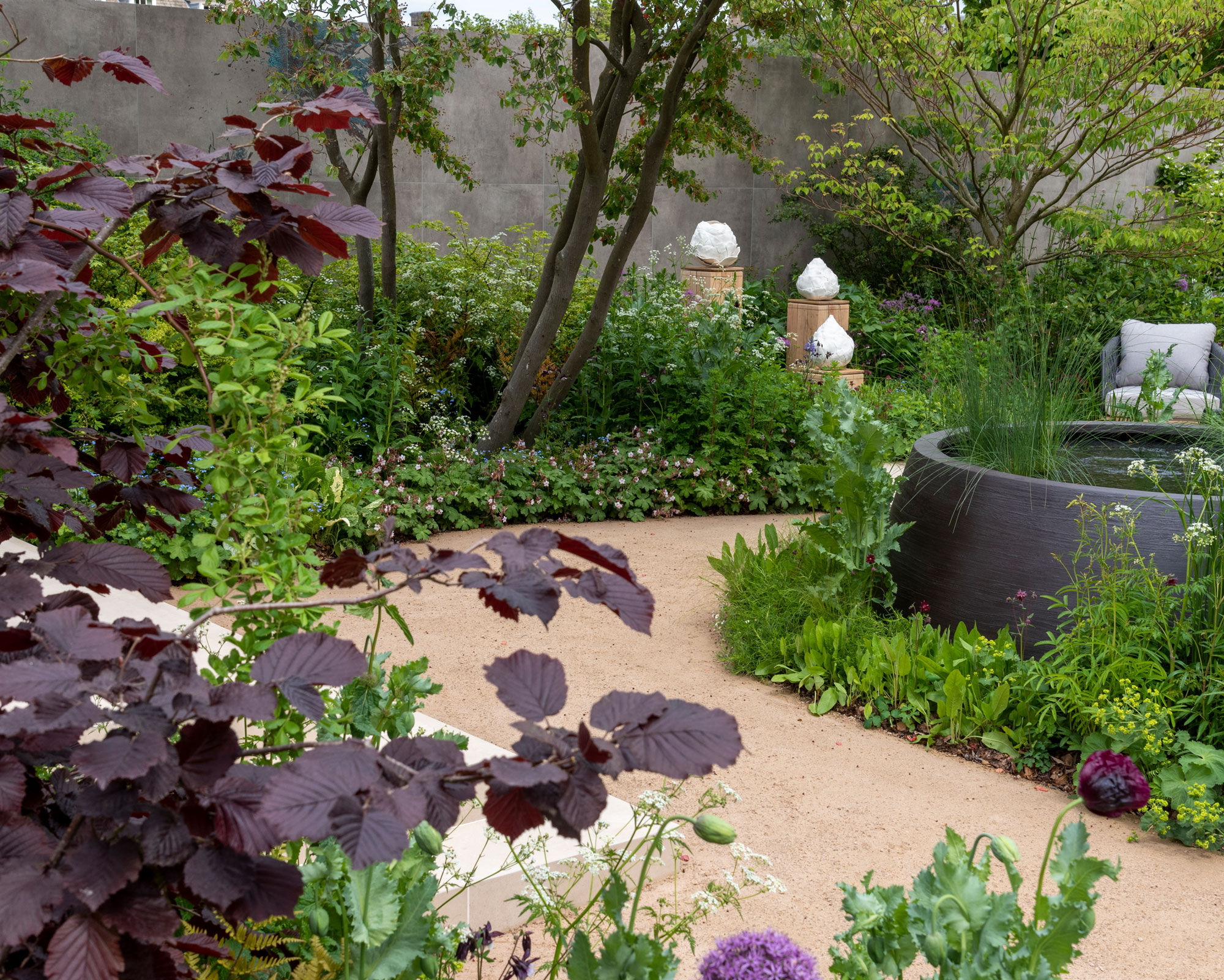 modern garden design with purple planting, water feature, garden chair and multi-stemmed tree