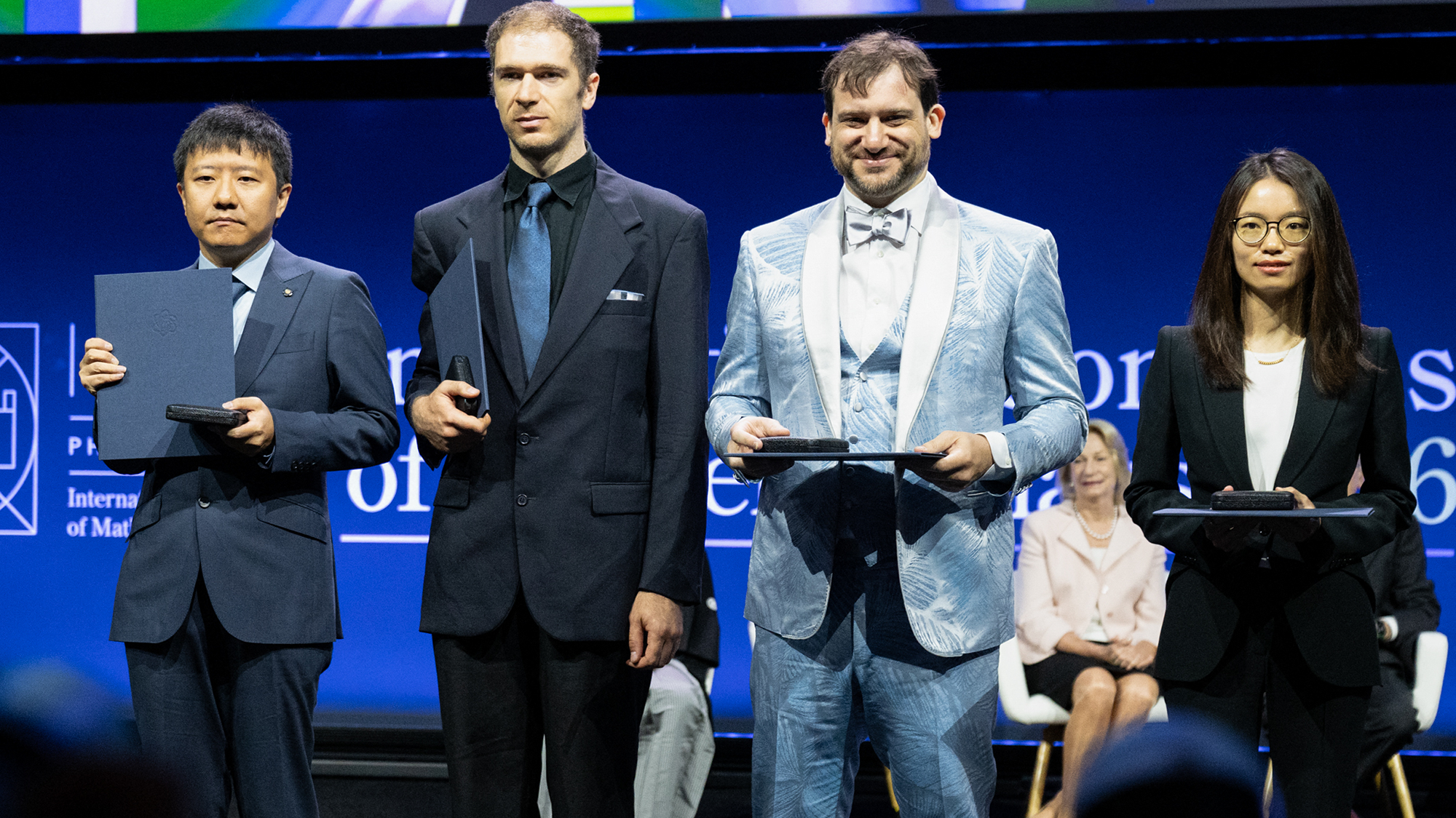 Four people stand on stage
