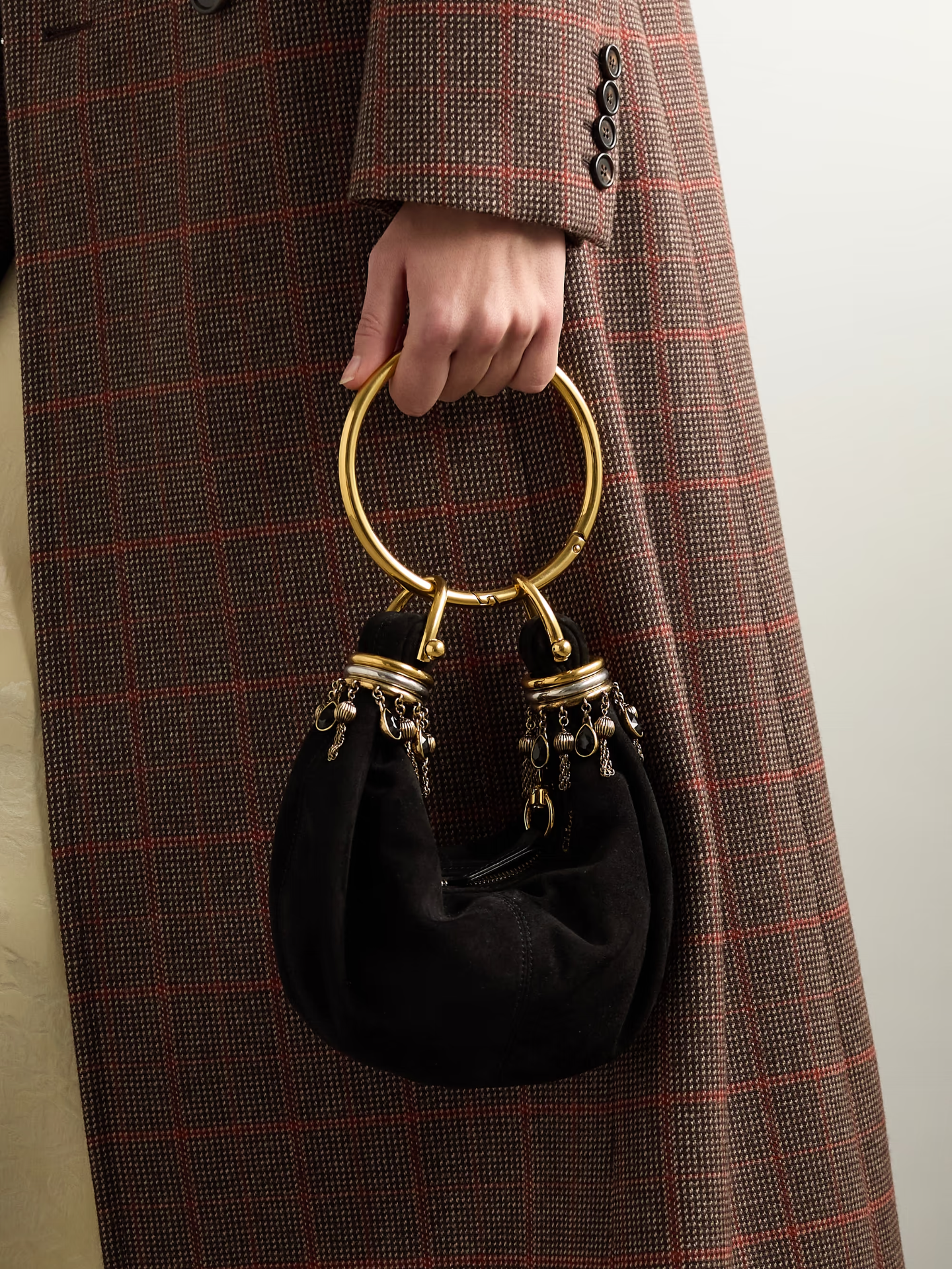A model holding a suede black bag with a bracelet-like handle and charms.