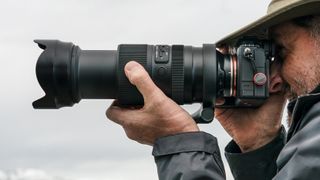 Objectif Tamron 50-300mm f/4.5-6.3 Di III VC VXD sur un appareil photo Sony tenu à hauteur de l'œil du photographe