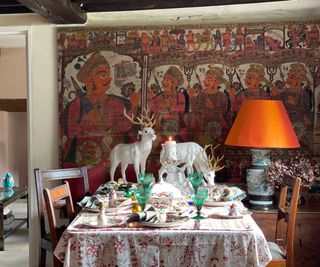 A Christmas dining table decorated with vintage textiles, glassware, and reindeer statues