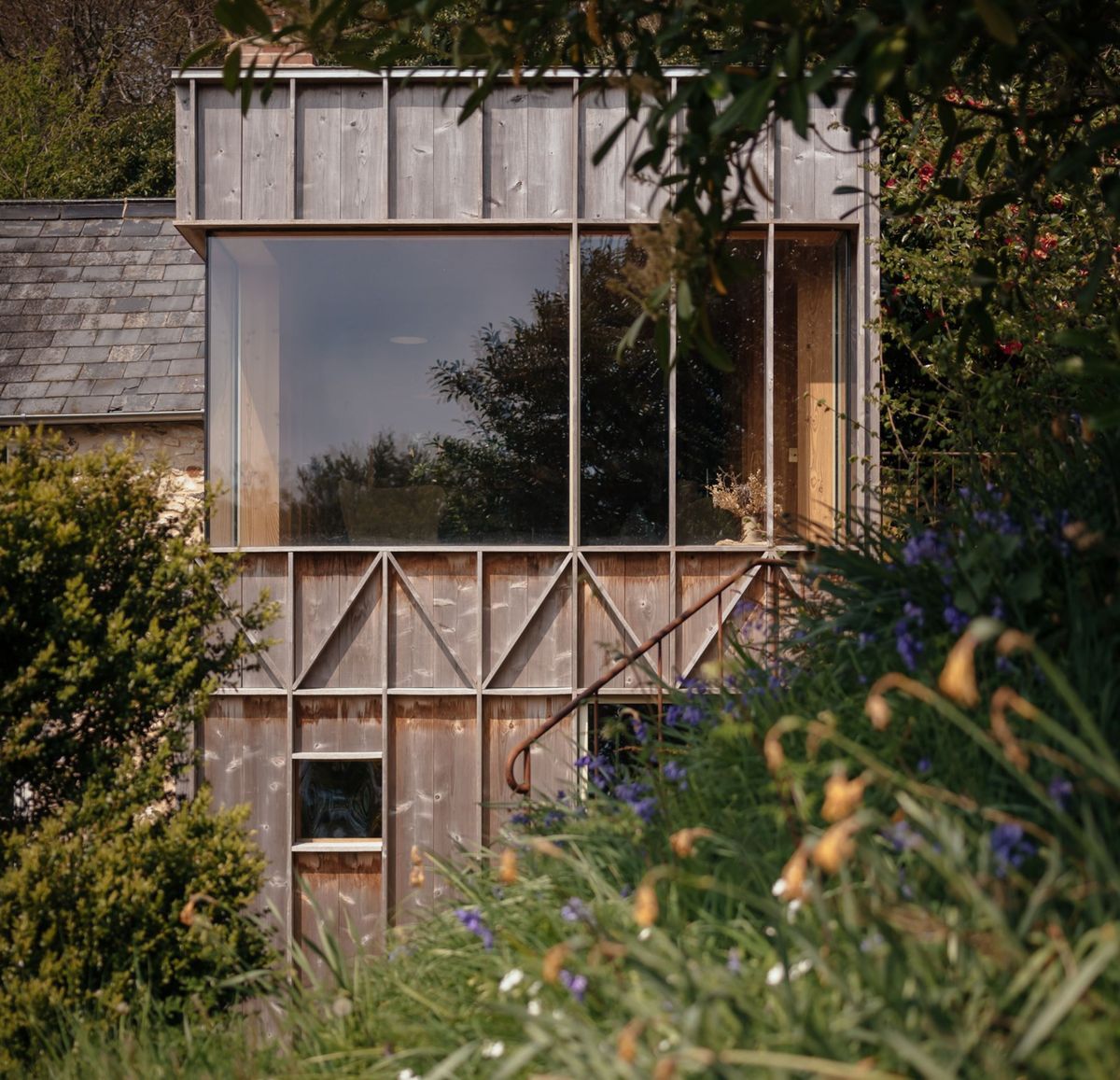 A timber cladded home with wall to ceiling windows