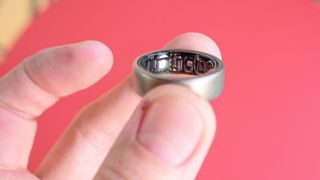 Amazfit Helio ring held in a user's finger's showing the sensors on the inside of the ring,