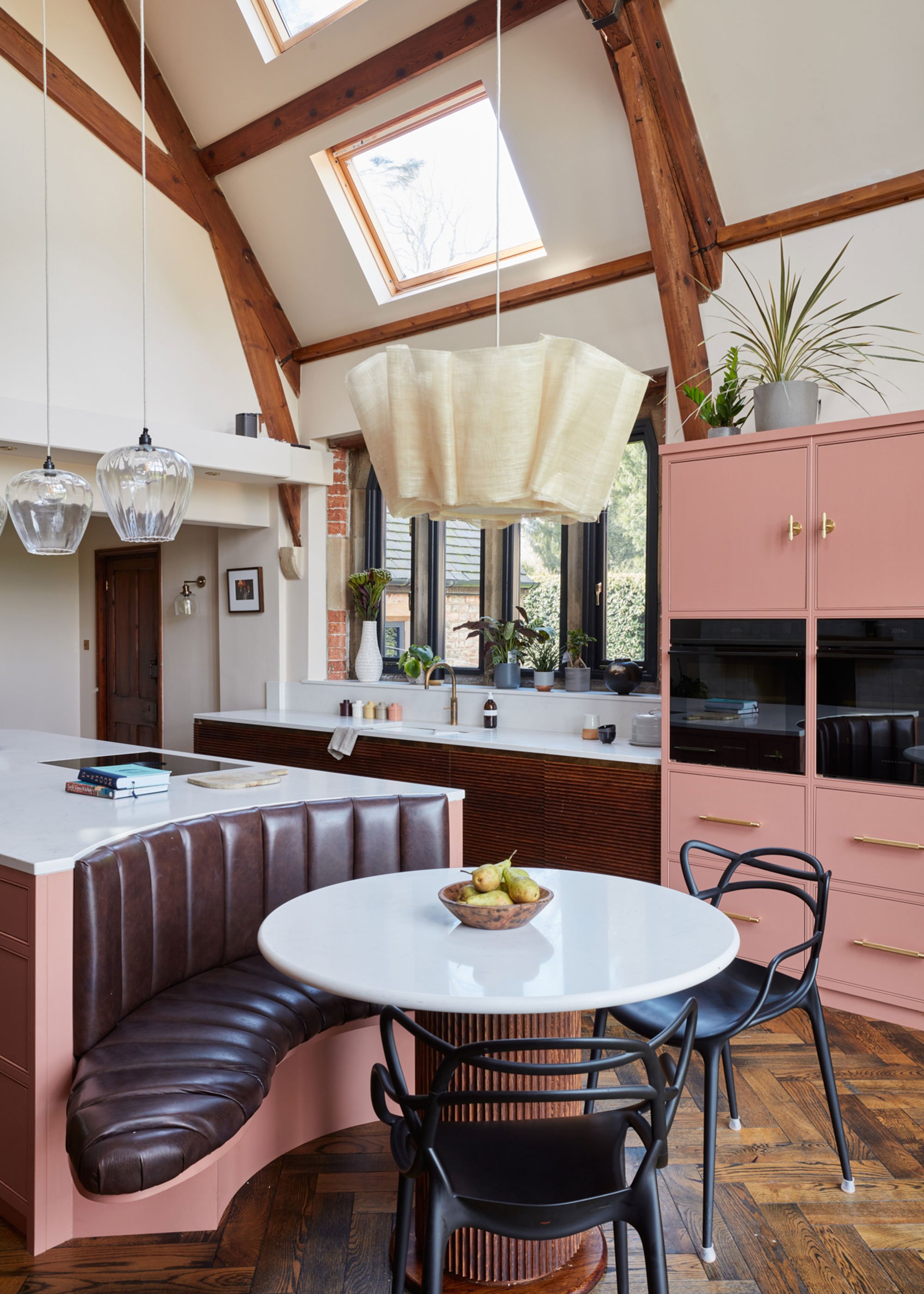 pink and brown kitchen with curved banquette seating and built-in ovens