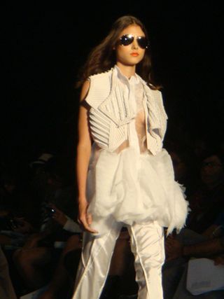 Model wearing a white outfit with a lot of pleating, ruffles and layers