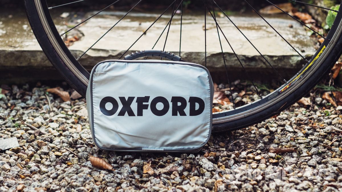 A bike cover in a silver case next to a bike wheel