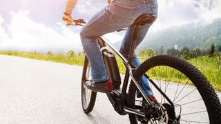 A man in jeans cycles on an Upway e-bike on a sunny day