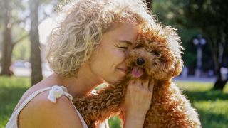 Owner nuzzling into her brown maltipoo dog