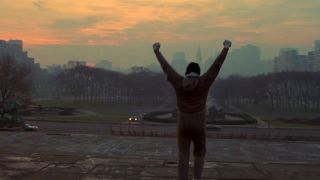 Rocky (Sylvester Stallone) raising his arms at the top of a big staircase overlooking Philadelphia