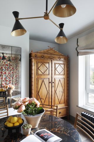 A dining room with a wooden wardrobe and pendant lights