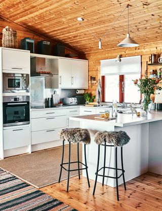 an open plan kitchen pace in a log cabin with stools and a wooden floor