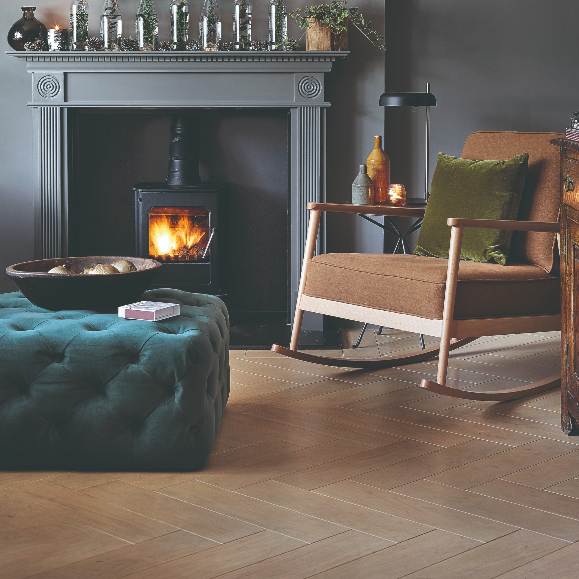 A living room colour drenched in dark grey, including the fireplace surrounding alit wood burning stove